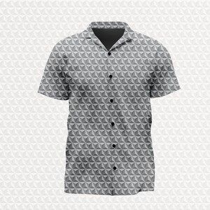 May include: A short-sleeved button-down shirt featuring a repeating geometric pattern of gray and white three-dimensional triangles. The shirt has a classic collar, a dark gray inner neckline, and a vertical row of five visible black buttons.