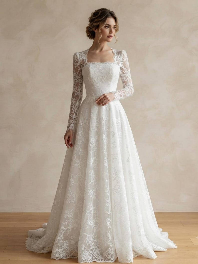 May include: A floor-length white lace gown featuring long sleeves, a square neckline, and a fitted bodice that transitions into a full, flowing skirt. The intricate floral lace pattern covers the entire garment, extending to the hemline.