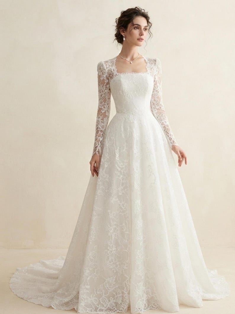 May include: A floor-length white wedding dress featuring long lace sleeves, a square neckline, and a fitted bodice that transitions into a full, flowing skirt with a train. The entire garment is covered in a delicate floral lace overlay pattern.