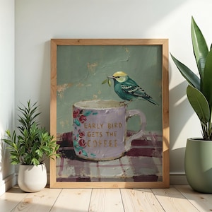 May include: A framed painting featuring a light purple mug with floral accents and the text "EARLY BIRD GETS THE COFFEE" in gold lettering. A small blue and yellow bird with a green leaf in its beak is perched on the rim of the mug.