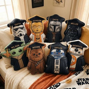 以下が含まれることがあります： 黒い角帽と黄色い房を身に着けたスター・ウォーズのキャラクターの形をした8つのクッション。各クッションには、スミス、ジョンソン、デイビス、ミラー、ウィルソン、ムーア、テイラー、アンダーソンの名前が記されています。キャラクターは、ストームトルーパー、C-3PO、マンダロリアン、ダース・ベイダー、グローグー、チューバッカ、R2-D2、BB-8です。
