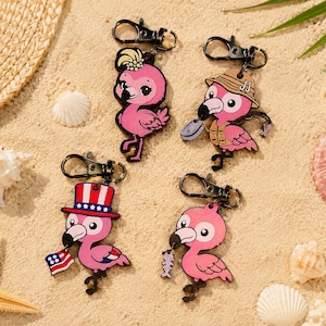 May include: Four pink flamingo keychains with black lobster clasps. One wears a yellow flower, one a tan fishing hat and vest, one a red, white, and blue top hat holding a flag, and one holds a fish skeleton. Each features a unique cartoon design.