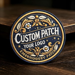 Könnte beinhalten: Ein kreisförmiger bestickter Aufnäher mit dunkelblauem Hintergrund und goldenem Rand. Er zeigt weiße und goldene florale Filigranmuster, Sterne sowie den Text CUSTOM PATCH, YOUR LOGO und EMBROIDERY PATCH in weißem und goldenem Garn.