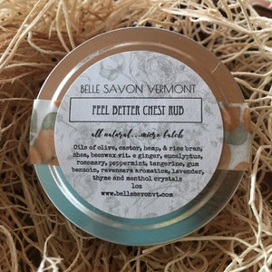 May include: A small, round, teal-colored tin with a white label that reads "BELLE SAVON VERMONT FEEL BETTER CHEST RUB all natural.. micro batch Oils of olive, castor, hemp, & rice bran, shea, beeswax vit. e ginger, eucalyptus, rosemary, peppermint, tangerine, gum benzoin, ravensara aromatica, lavender, thyme and menthol crystals 1oz www.bellesavonvt.com".