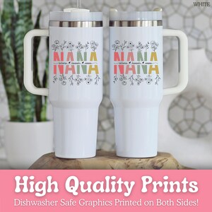 May include: Two white stainless steel tumblers with handles and lids. Each features the word NANA in large, colorful block letters with floral line art above and below. The names Victoria, Hannah, and Emma are printed in black script between the letters.