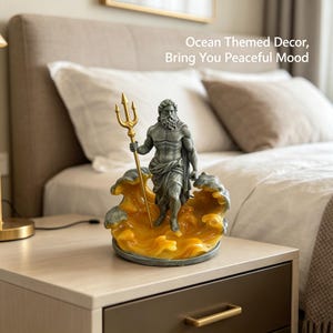 K&ouml;nnte beinhalten: Graue Statue eines muskul&ouml;sen Mannes, der einen goldenen Dreizack h&auml;lt und auf einer gelb-grauen Wellenbasis steht. Die Statue tr&auml;gt die Aufschrift "Ocean Themed Decor, Bring You Peaceful Mood". Die Statue steht auf einem Nachttisch.