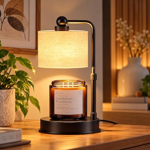 May include: A black metal candle warmer lamp with a cylindrical beige fabric shade. The lamp sits on a circular base holding a brown glass candle jar with a white label reading Smokeless Flameless, 50 hours burn time, 7 oz (200 g).