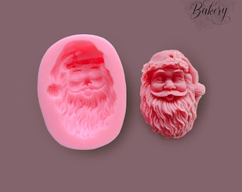 May include: A pink silicone mould of a Santa Claus face. The mould is in the shape of a head and has a detailed design of Santa's face, beard, and hat.
