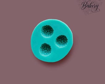 May include: A round, teal-colored silicone mold featuring three circular indentations with a textured, granular surface pattern. The mold is smooth on the exterior and includes the text My Little Bakery printed in the upper right corner.