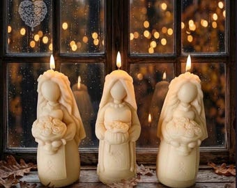 May include: Three cream-colored wax candles shaped like figures wearing veils and holding bouquets of flowers. Each candle features a lit wick at the top, creating a warm glow. The figures have smooth, rounded features and are standing upright.
