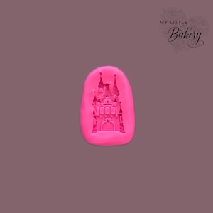 May include: Pink silicone mould with a detailed castle design. The mould is shaped like a rounded rectangle.