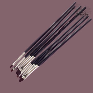 May include: A set of seven black handled paint brushes with silver ferrules. The brushes are arranged in a fan shape with the handles pointing towards the top of the image. The text "My Little Bakery" is visible in the top right corner of the image.