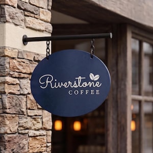 May include: An oval-shaped dark blue hanging sign suspended by two black chains from a horizontal black metal bar. The sign features the white text Riverstone COFFEE with a small graphic of two coffee beans above the word Coffee.