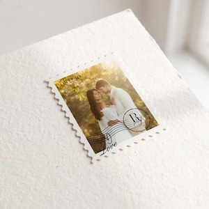 K&ouml;nnte beinhalten: Eine rechteckige Briefmarke mit einem Foto eines Paares in einer Au&szlig;enumgebung. Die Briefmarke enth&auml;lt das Datum 08.12.30, ein kreisf&ouml;rmiges Monogramm mit den Buchstaben R und G sowie das Wort Love in einer kursiven Schriftart.