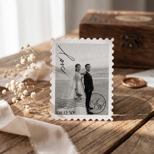 K&ouml;nnte beinhalten: Eine rechteckige Karte im Briefmarkenstil mit einem Schwarz-Wei&szlig;-Foto eines Paares am Strand. Die Karte enth&auml;lt den kursiven Text Love, das Datum 08.12.30 und ein kreisf&ouml;rmiges Monogramm mit den Buchstaben AW.