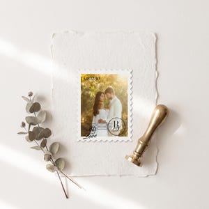 K&ouml;nnte beinhalten: Eine rechteckige Briefmarke mit einem Foto eines Paares in einer sonnendurchfluteten Au&szlig;enumgebung. Die Briefmarke enth&auml;lt das Datum 08.12.30, ein kreisf&ouml;rmiges Monogramm mit den Buchstaben R und A sowie das Wort Love in Schreibschrift.