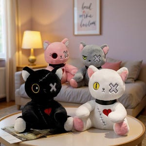 May include: Four plush cat toys in black, white, pink, and grey. Each cat features a black collar, a stitched red heart on the chest, one circular eye, and one eye shaped like an X. The black cat has white stitching on its head, and the white cat has black stitching on its torso.