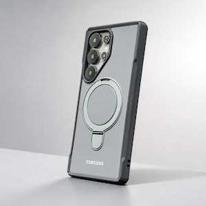 May include: A dark gray smartphone case with a translucent back panel and a built-in circular magnetic ring stand. The case features a cutout for the camera array and the Samsung logo printed in white at the bottom of the rear surface.
