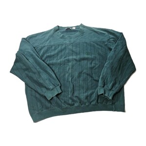 May include: A dark teal long-sleeve sweatshirt featuring a crew neckline and a subtle vertical pinstripe pattern throughout the body and sleeves. The garment includes a small embroidered logo on the upper right chest area and ribbed cuffs.