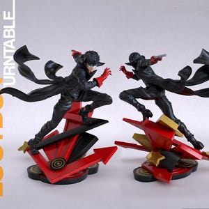 May include: Two dynamic action figures of a character wearing a black trench coat, black pants, red gloves, and a white mask. The figures are posed in mid-air above a red and black geometric base featuring star shapes and arrow motifs.