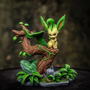 May include: A small, light yellow creature with large, pointed green ears and a leaf-like tail sits atop a textured brown tree branch. The base features green foliage, grey rocks, and a winding green vine wrapping around the wooden structure.