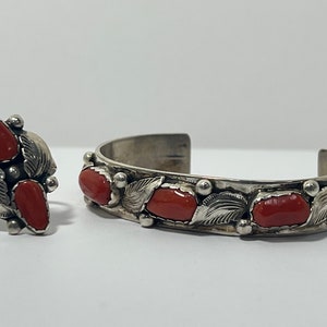 May include: A set of sterling silver jewelry featuring red coral stones. The set includes a ring and a bracelet with a leaf design.