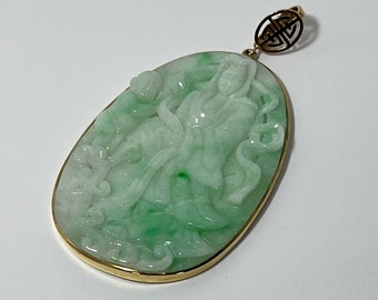 May include: A jade pendant with a detailed carving of a woman in a flowing robe. The pendant is set in a gold frame and has a gold bail with a Chinese knot design.