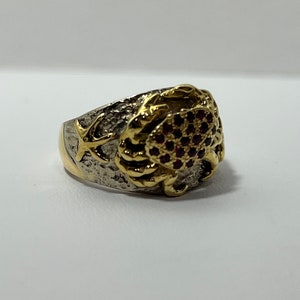 May include: A gold and silver ring with a crab design. The crab is decorated with purple gemstones.