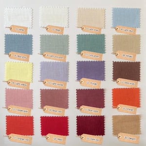 May include: A color swatch chart featuring twenty rectangular fabric samples with pinked edges, arranged in a grid. Each sample is labeled with a numbered tan paper tag, including colors like white, beige, khaki, blue, gray, yellow, purple, and red.