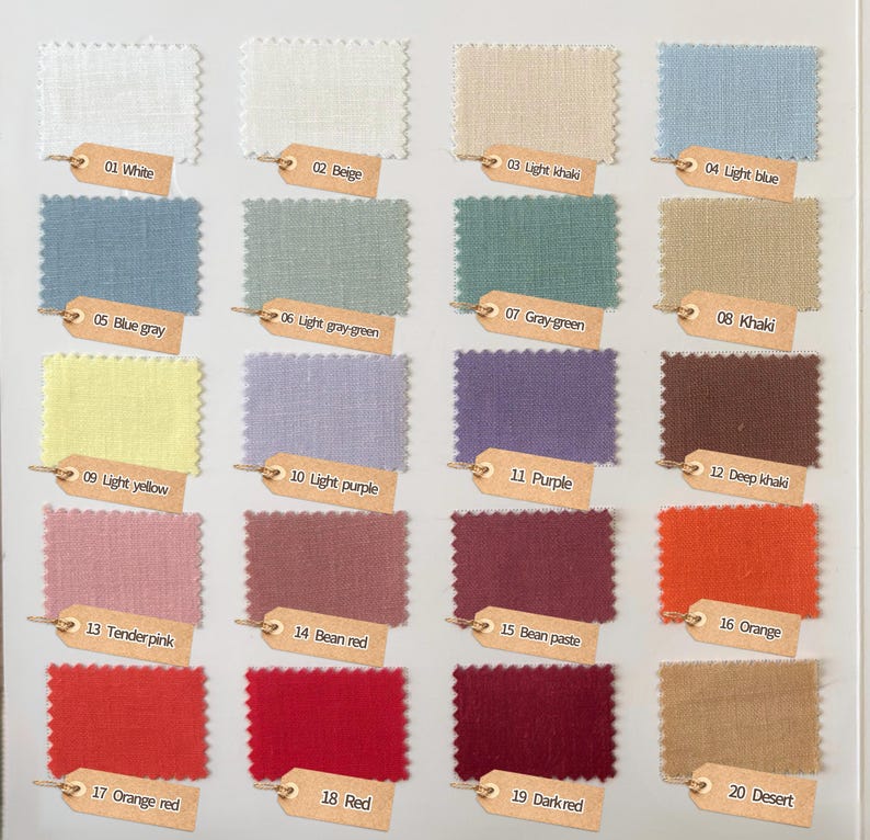 May include: A color swatch chart featuring twenty rectangular fabric samples with pinked edges, arranged in a grid. Each sample is labeled with a numbered tan paper tag, including colors like white, beige, khaki, blue, gray, yellow, purple, and red.