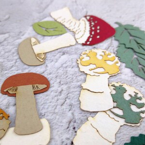 May include: Assortment of paper craft mushroom shapes in various colors, including red, yellow, green, and brown. The mushrooms are cut out of paper and have a rustic, vintage look.