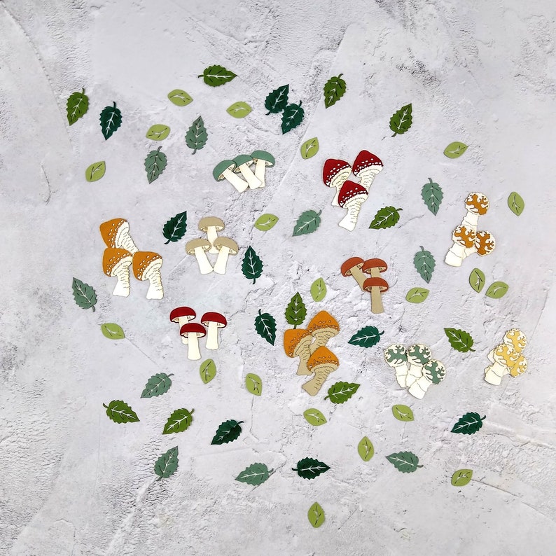 May include: A collection of colorful mushroom-shaped paper cutouts on a white textured background. The mushrooms are in various shades of red, orange, yellow, and green.