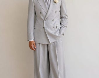Abito doppiopetto grigio chiaro, pantaloni a gamba larga, completo da sposo moderno ed elegante.