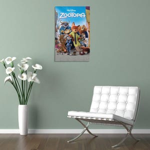 May include: A framed Zootopia movie poster featuring a group of anthropomorphic animal characters. The poster has a blue background with the movie title in white and the Disney logo. The characters include a fox, a rabbit, and a lion.