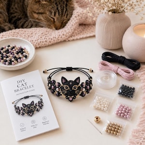 May include: A DIY cat bracelet kit featuring a black macrame bracelet with a central cat face charm, black and pink pearl beads, gold-tone beads, black and pink cord, a needle, and an instruction booklet titled DIY CAT BRACELET.