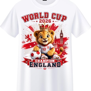 Könnte beinhalten: Weißes T-Shirt mit einer Grafik eines Löwen mit Krone und Fußballtrikot, der einen Fußball hält. Das Shirt zeigt den Text "WORLD CUP 2026" und "CHAMPION ENGLAND" in Rot und Blau.