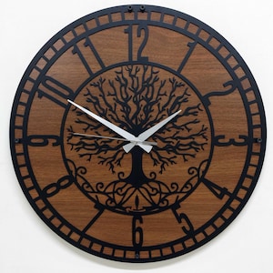 Può includere: Un orologio da parete rotondo con un quadrante in legno marrone scuro e una cornice in metallo nero. L'orologio presenta un design ad albero della vita al centro e numeri neri. Le lancette dell'orologio sono argentate.