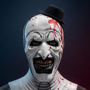 May include: A white clown mask featuring a black nose, black eye markings, and a wide, toothy grin. The mask is splattered with red paint resembling blood and is topped with a small black bowler hat. A black string hangs from the chin area.