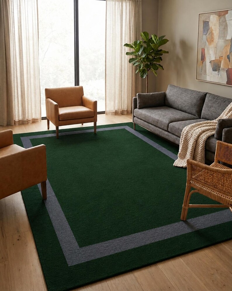 May include: A rectangular area rug featuring a deep forest green center field enclosed by a wide, solid charcoal gray border. The rug has a low-pile texture and is positioned flat on a light-toned wooden floor, serving as a central floor covering.