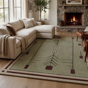 Puede incluir: Una alfombra rectangular que presenta un campo verde salvia con un patrón geométrico de líneas negras y acentos cuadrados de color rojo oscuro. La alfombra tiene un borde ancho en tono beige claro con una franja roja oscura en el perímetro.