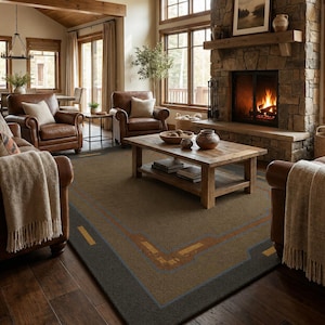 May include: A large rectangular area rug featuring a dark brown center with a geometric border pattern in light brown and blue lines. The rug is positioned on a dark wood floor in a living room with leather armchairs and a wooden coffee table.