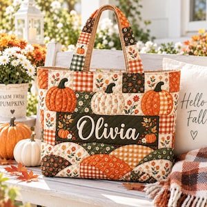 Könnte beinhalten: Eine gesteppte Tragetasche mit einem Patchwork-Design aus orangefarbenen Kürbissen, Herbstblumen und Karomustern in Orange-, Grün- und Cremetönen. Das mittlere Feld zeigt den Namen Olivia in weißer Schreibschrift auf dunkelgrünem Hintergrund.