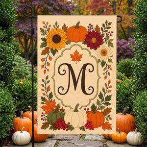 May include: A rectangular garden flag with a cream background featuring a central dark brown letter M inside a decorative border. The design includes orange pumpkins, a green pumpkin, a white pumpkin, sunflowers, red dahlias, and autumn leaves.