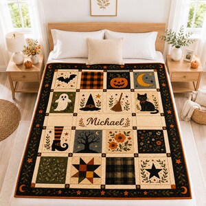 May include: A rectangular quilt featuring a grid of squares with Halloween-themed illustrations including a bat, pumpkin, ghost, witch hat, broom, black cat, tree, and flowers. The center square displays the name Michael in cursive script.