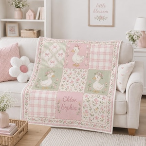 Könnte beinhalten: Eine personalisierte Patchwork-Decke in zarten Rosa- und Salbeigrüntönen. Das Design zeigt Illustrationen von Enten mit Hüten und Schleifen, Blumenmuster und Karos. Der Name Chloe Sophia ist in der Mitte der Decke aufgedruckt.
