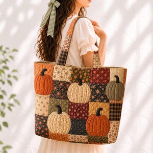 May include: A quilted tote bag featuring a patchwork design of various autumn-themed fabrics in shades of orange, brown, cream, and black. The bag displays multiple appliquéd pumpkin motifs with black stems and has two matching fabric shoulder straps.