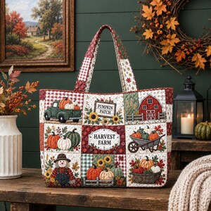May include: A quilted tote bag featuring a patchwork design with autumn-themed illustrations including a green truck, a red barn, a scarecrow, pumpkins, sunflowers, and signs that read Pumpkin Patch and Harvest Farm with red and white gingham accents.