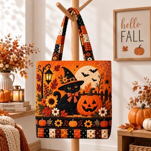 May include: A quilted tote bag featuring a black cat wearing a witch hat, a jack-o'-lantern, sunflowers, and autumn leaves. The design includes a street lamp, bats, and a spider web against a full moon. The bottom border has a pumpkin and floral pattern.