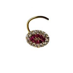 May include: A gold nose ring featuring an oval-shaped cluster of small, deep pink stones at the center, surrounded by a halo of tiny, clear, sparkling white stones. The piece includes a curved gold wire stem for secure placement and attachment.