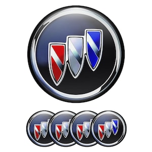 May include: A set of five circular Buick emblems featuring a dark blue background with three diagonal shields in red, silver, and blue. Each emblem has a polished chrome border and a glossy finish, displaying the iconic automotive brand logo.